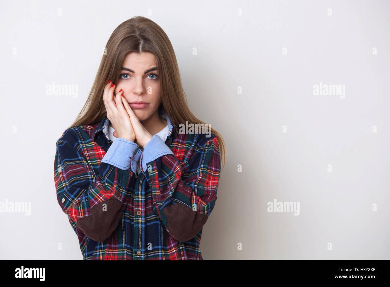 Portrait de studio de triste à la jeune femme en chemise à carreaux posant contre mur. Banque D'Images