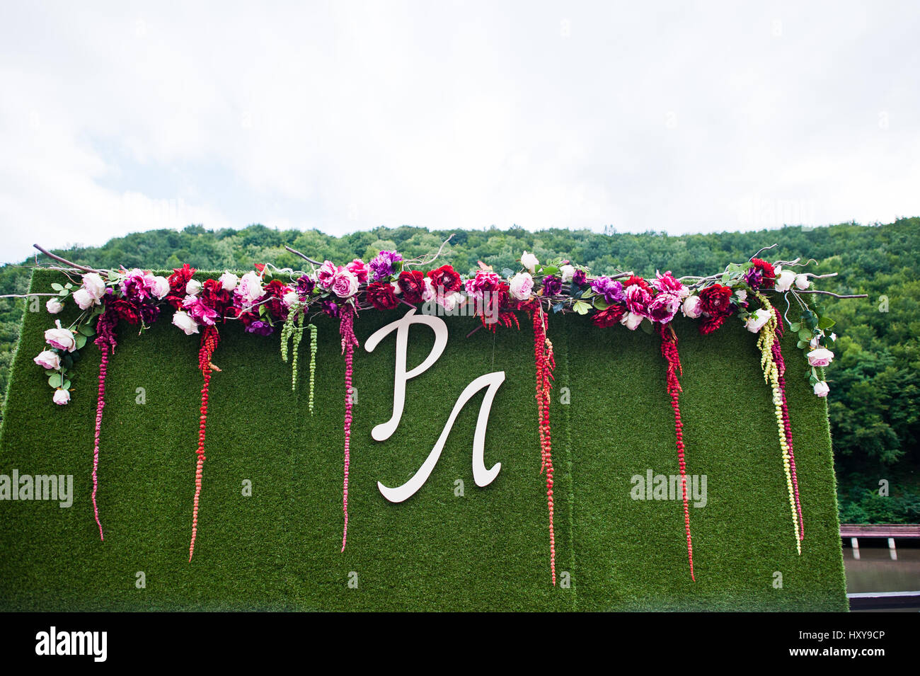 Zone de photo de mariage de gazon artificiel, fleurs et grande lettre de jeunes mariés d'initiales. Banque D'Images