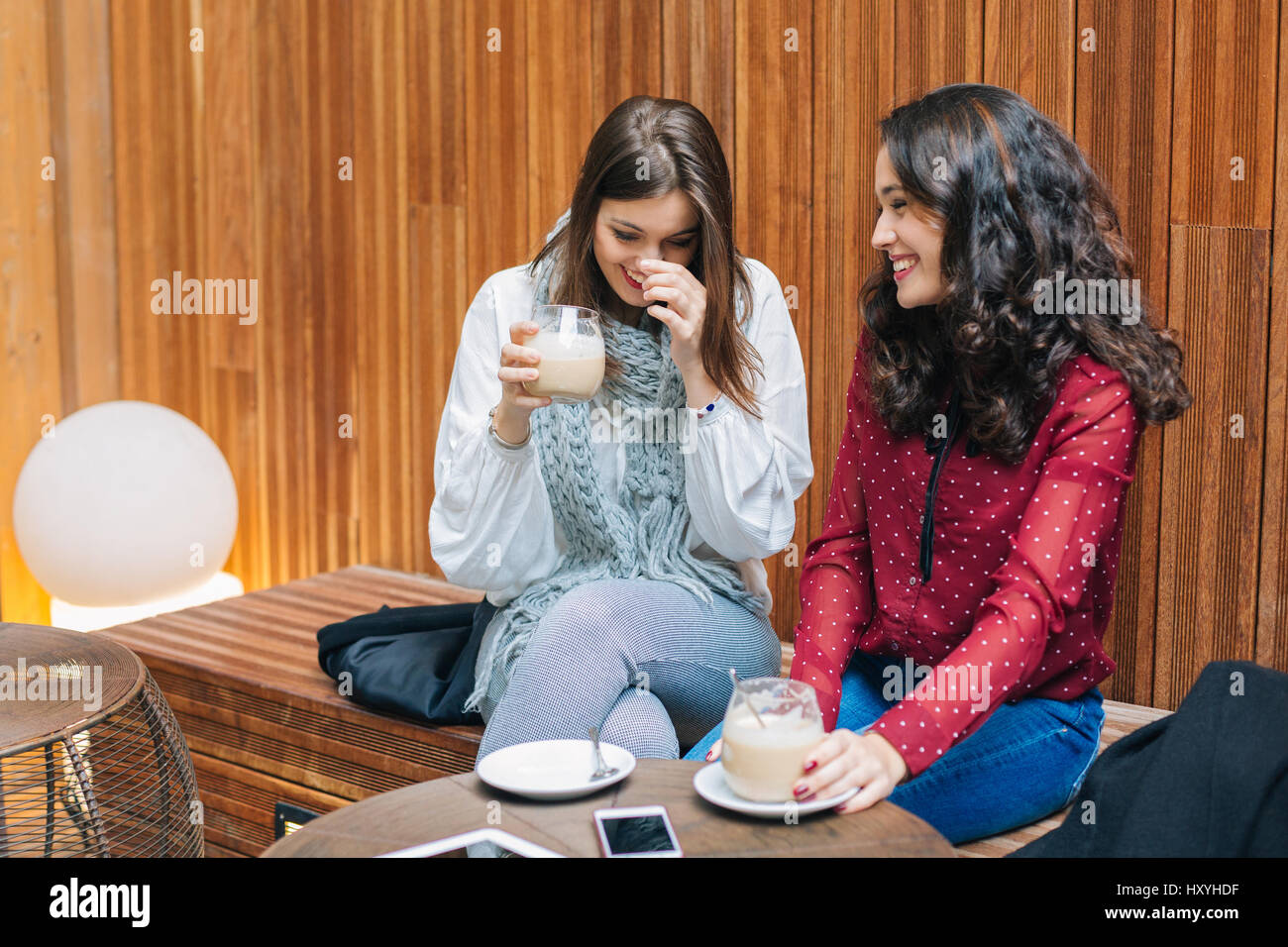Jeune femme en riant tout en prenant un café dans un café Banque D'Images