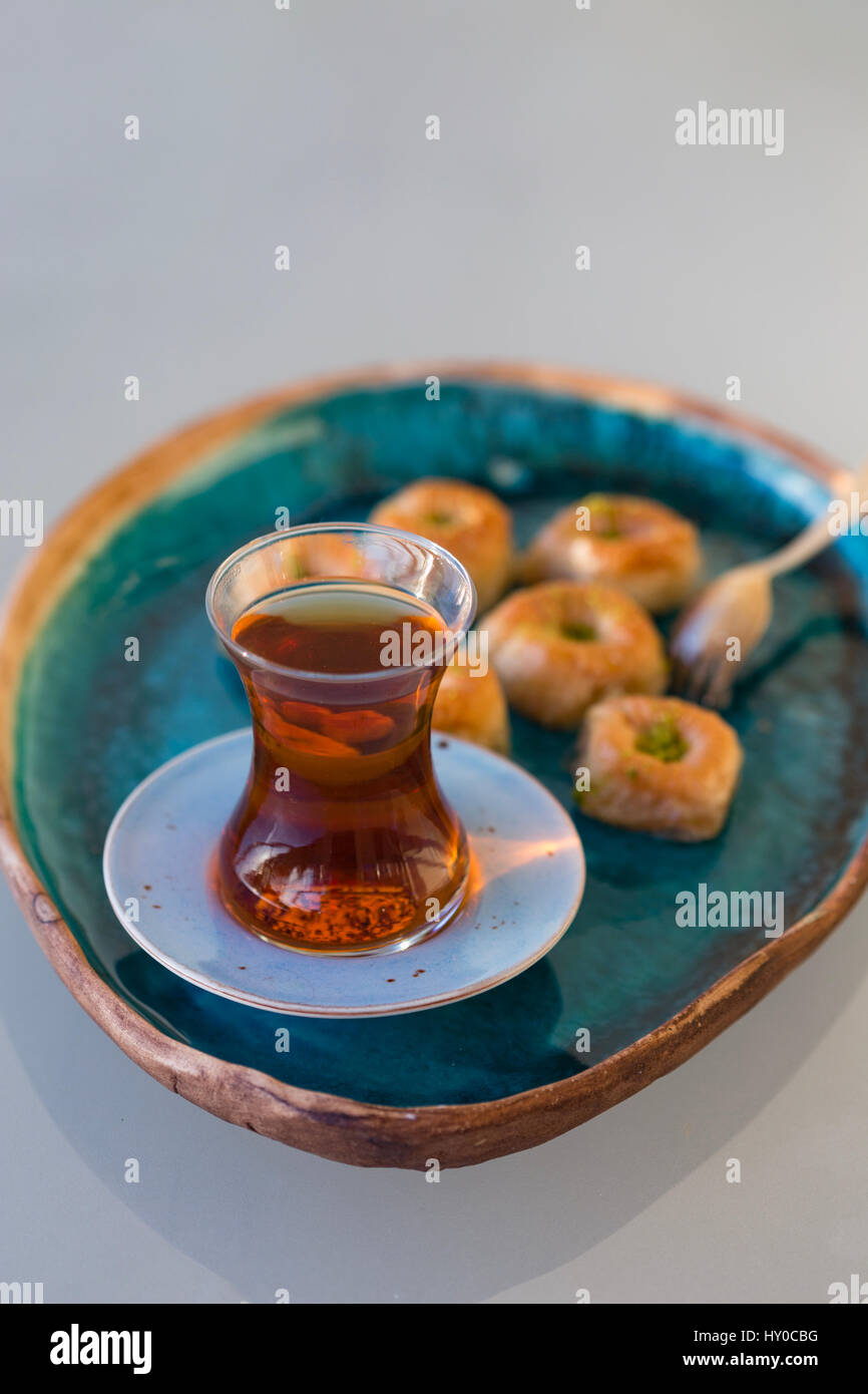Du thé turc et baklava placés dans le bac en céramique turquoise sur fond clair Banque D'Images