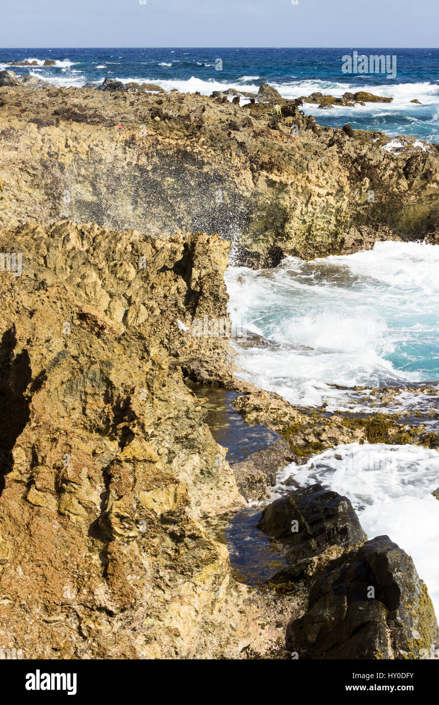 Les eaux bleu azur de la mer des Caraïbes écraser sur la côte nord de Aruba, près du pont naturel s'est effondré et les petits ponts. Banque D'Images