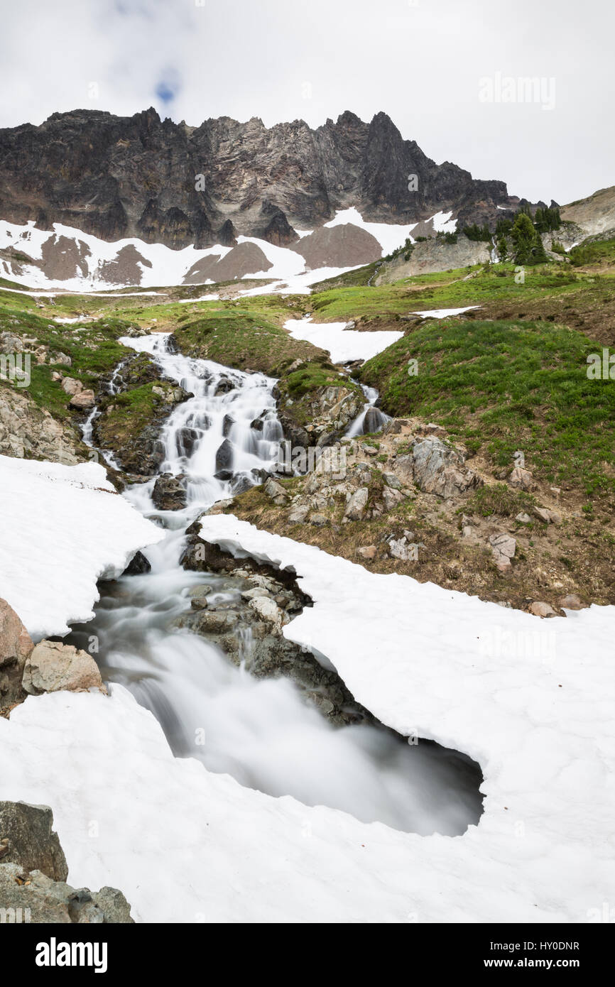 La fonte des neiges au printemps créé ce ruisseau qui a coupé son chemin sous la neige restante, laissant un pont de neige dangereuses. ci-dessus, un aec rocheuse escarpée Banque D'Images