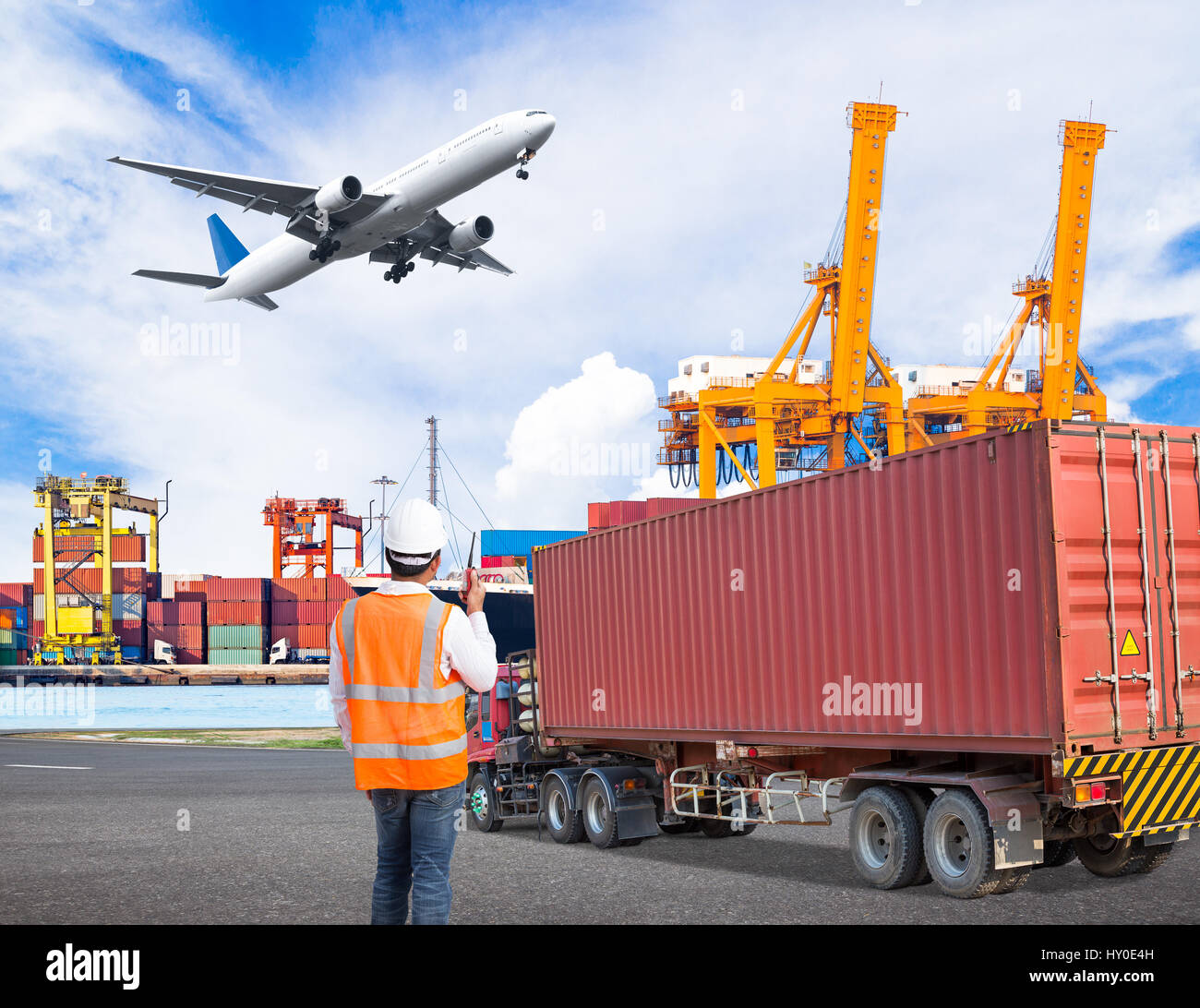 Docker en conversation sur le talkie-walkie pour contrôler le chargement de conteneur dans un port industriel avec chariot de transport et cago flyin avion Banque D'Images