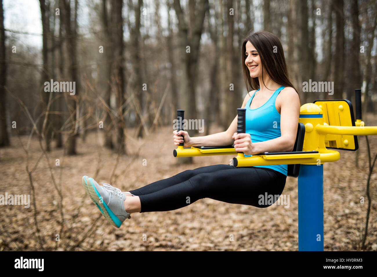 Portrait de jeune femme forte hanging on wall bars avec ses jambes. Femme Fitness jambe de suspension de la scène soulève sur l'extérieur. Banque D'Images