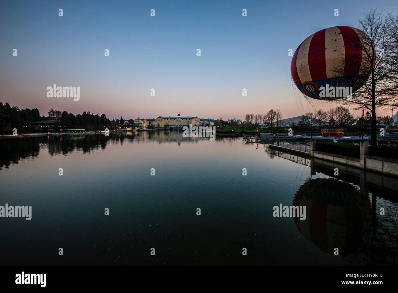 Hôtel Newport Bay Club et ballon panoramique à Disneyland Paris EuroDisney, vue de l'autre côté du lac Disney au crépuscule Banque D'Images