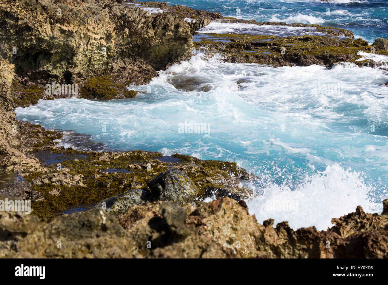 Les eaux bleu azur de la mer des Caraïbes écraser sur la côte nord de Aruba, près du pont naturel s'est effondré et les petits ponts. Banque D'Images