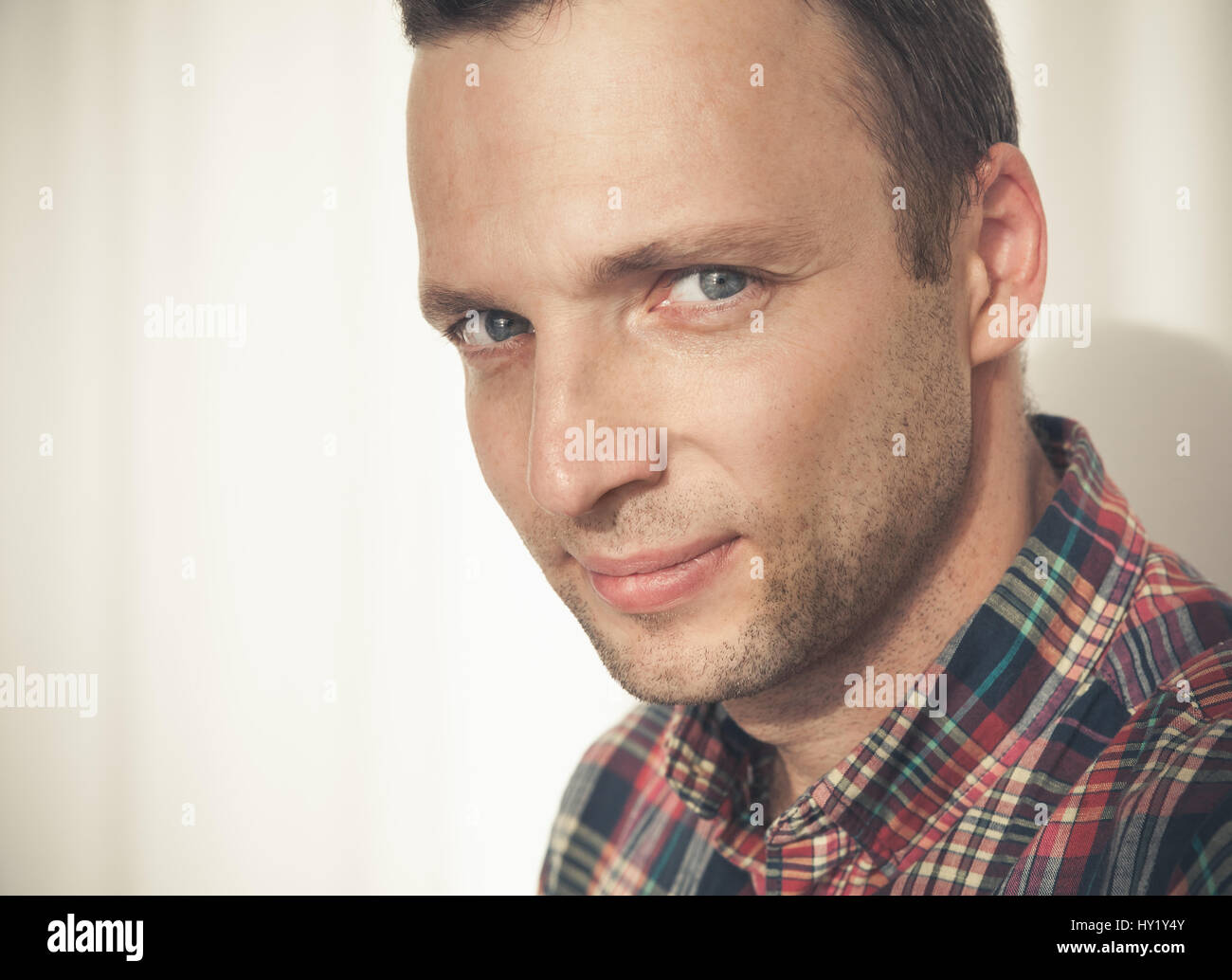 Close-up studio face portrait de jeune adulte homme européen en chemise décontractée colorée sur mur blanc avec ombre Banque D'Images