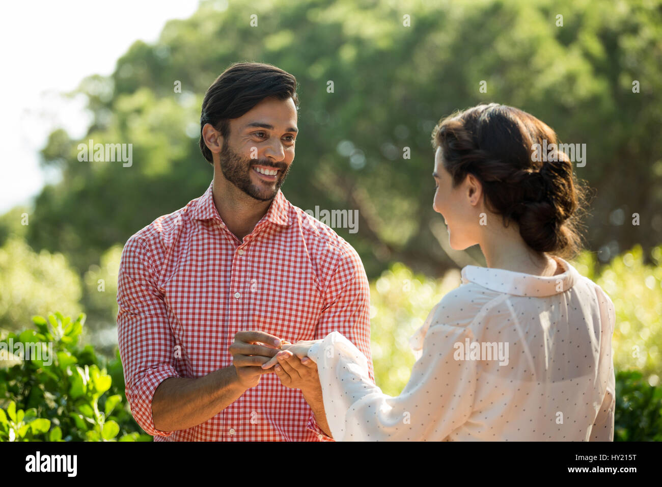 Happy man putting bague de fiançailles sur femme at park Banque D'Images