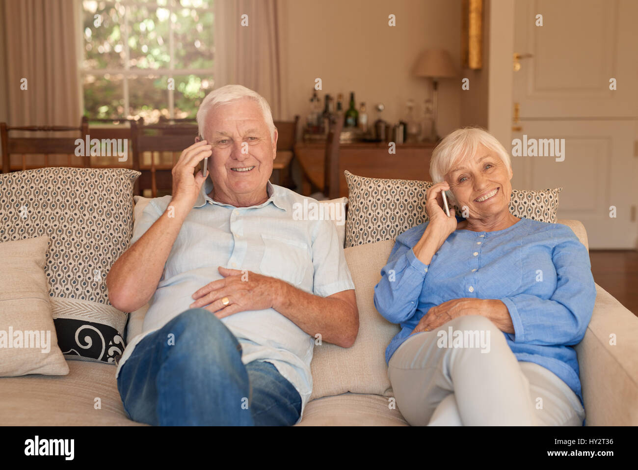 Heureux les personnes âgées à la maison de parler sur les téléphones cellulaires Banque D'Images