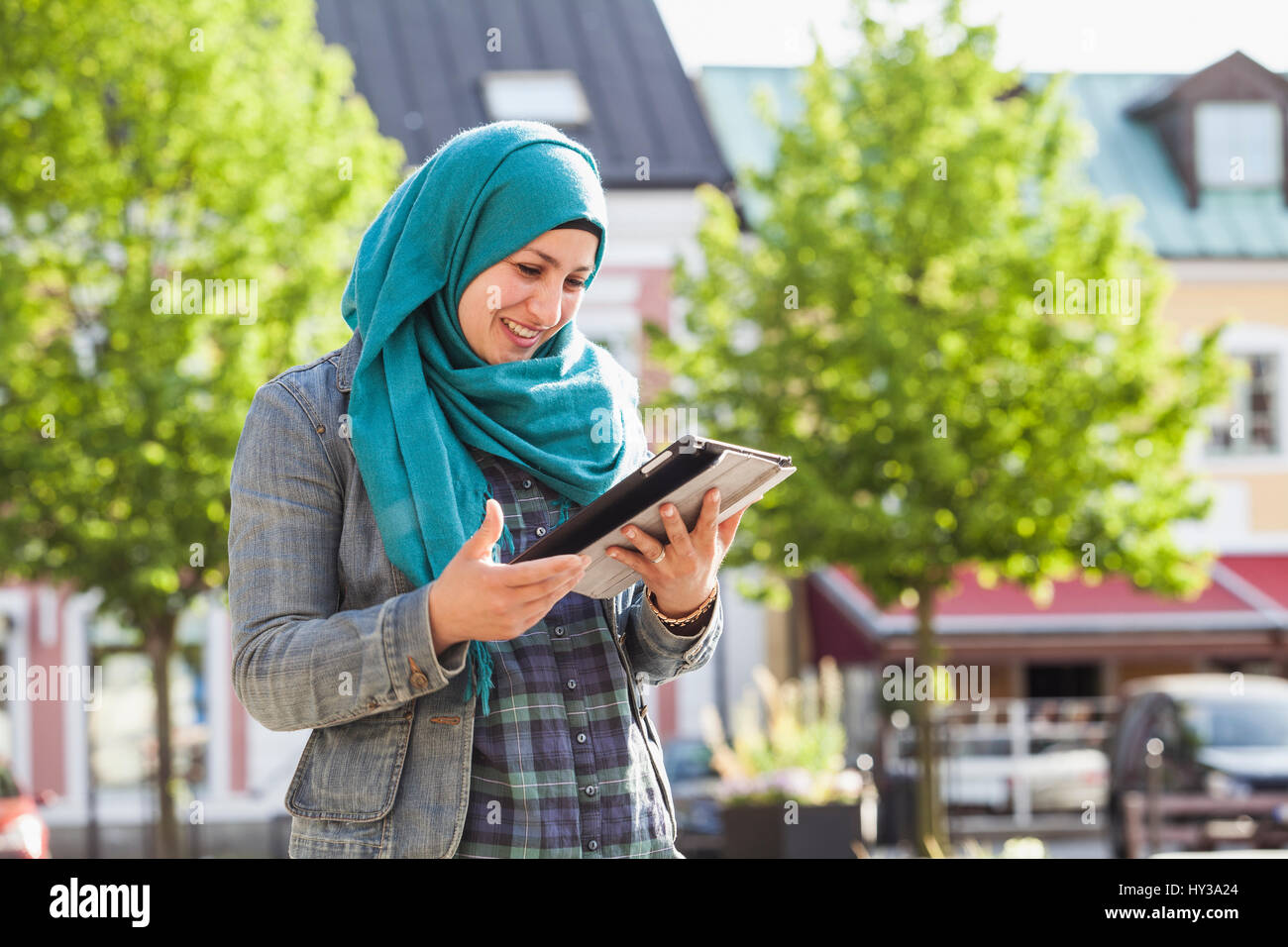 La Suède, Bleking, Solvesborg femme musulmane using tablet and smiling Banque D'Images