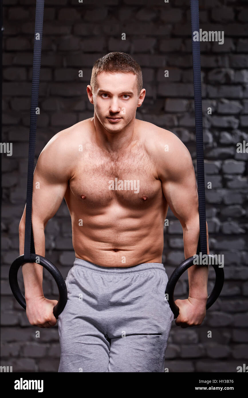 Exercice de base du Crossfit. Homme déterminé working out in gym tirez ups  avec anneaux de gymnastique pour la force Photo Stock - Alamy