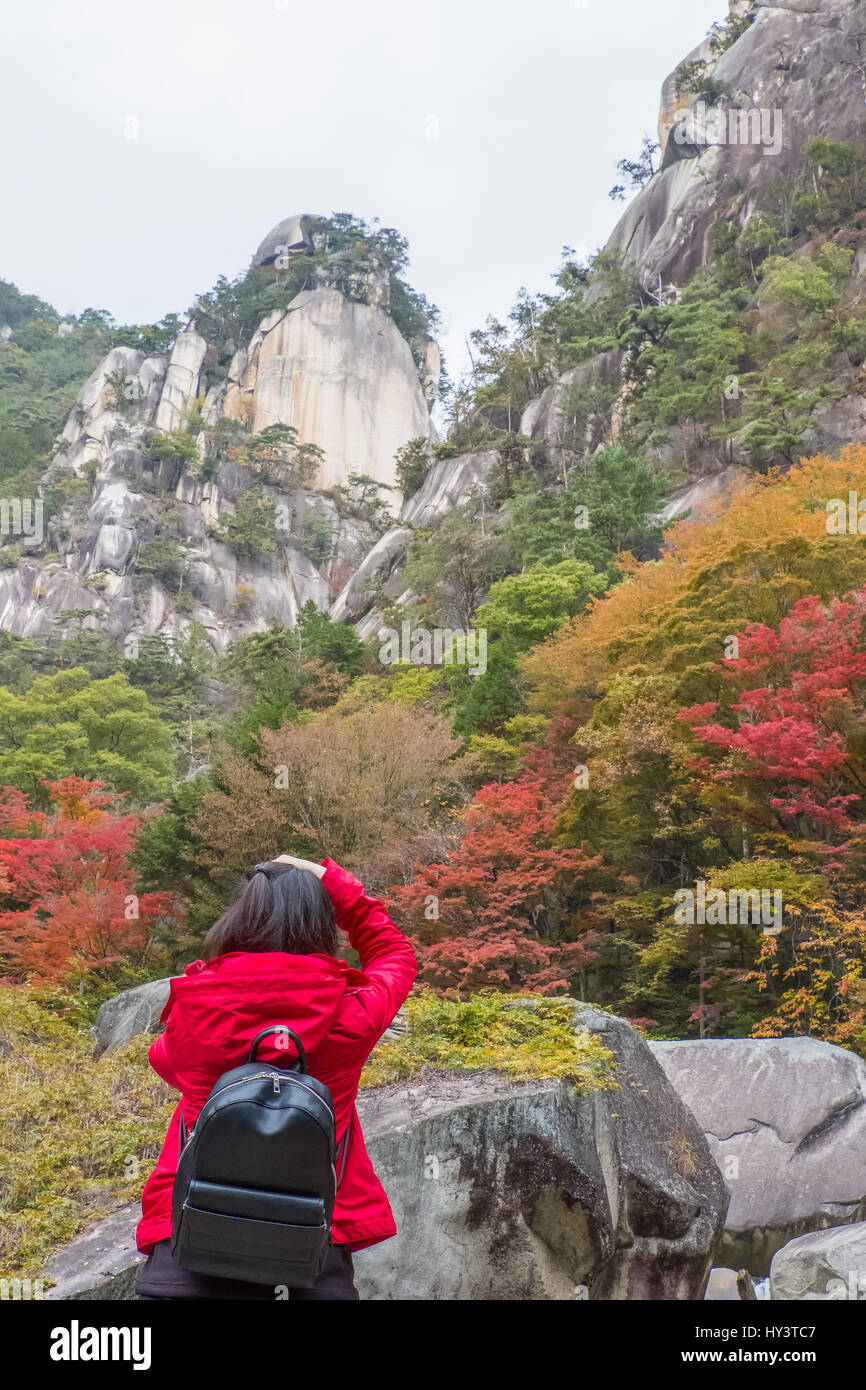 Woman in red jacket prend photo d'automne couleur des arbres au fond de gorges rocheuses dans Shosenkyo, Japon Banque D'Images