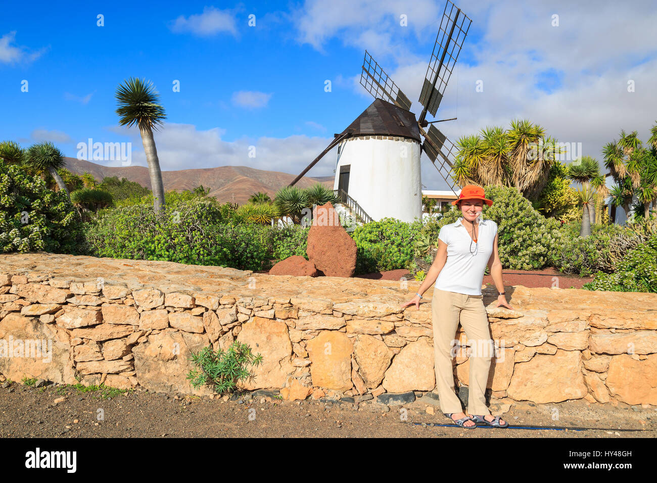 Jeune femme debout devant l'ancien moulin à vent dans des jardins tropicaux d'Antigua village, Fuerteventura, Îles Canaries, Espagne Banque D'Images