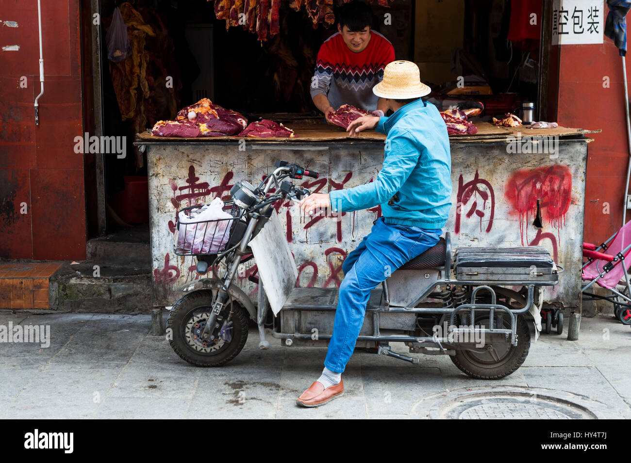 Lhassa, ancienne, l'homme sur un cyclomoteur en face de boucher Banque D'Images