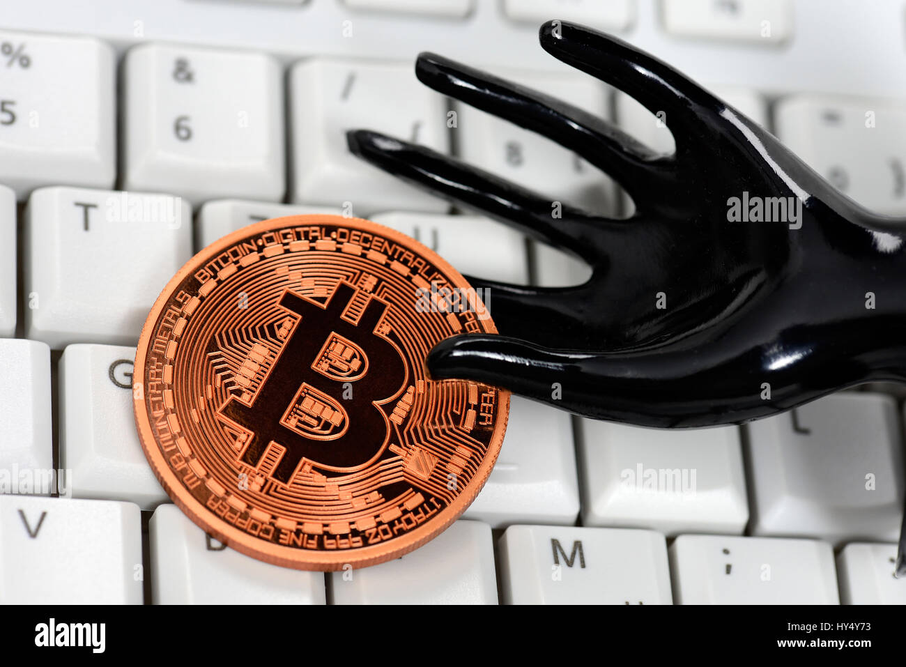 Pièce de monnaie avec la main noire et signe Bitcoin sur le clavier de l'ordinateur, l'utilisation de l'Bitcoin-Bezahlsystems par des criminels, Muenze Bitcoin-Zeichen mit und schwarze Han Banque D'Images