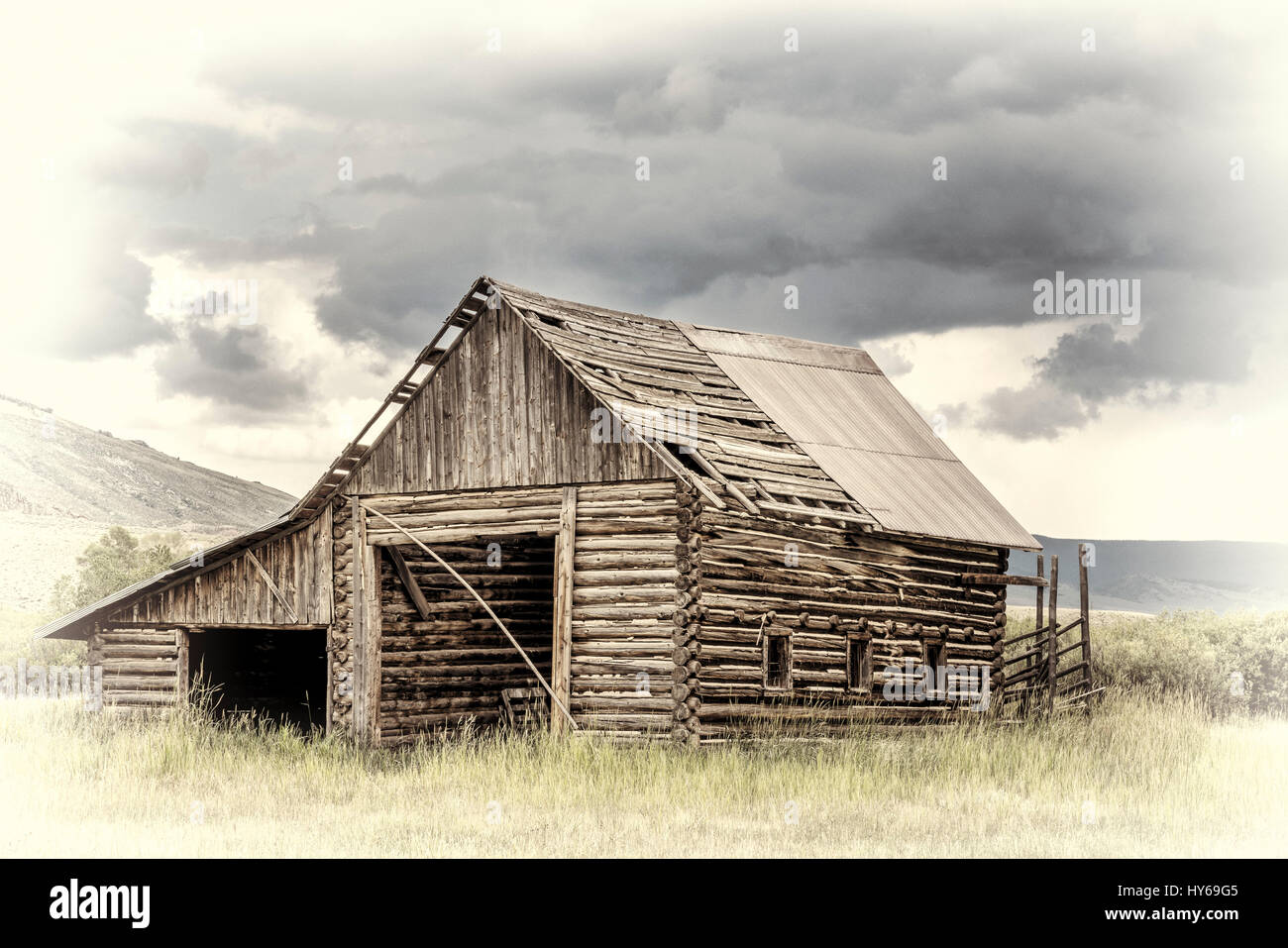 Ancienne, rustique, log barn dans les Montagnes Rocheuses du Colorado avec un ciel d'orage, traitement opalotype rétro teinté main Banque D'Images