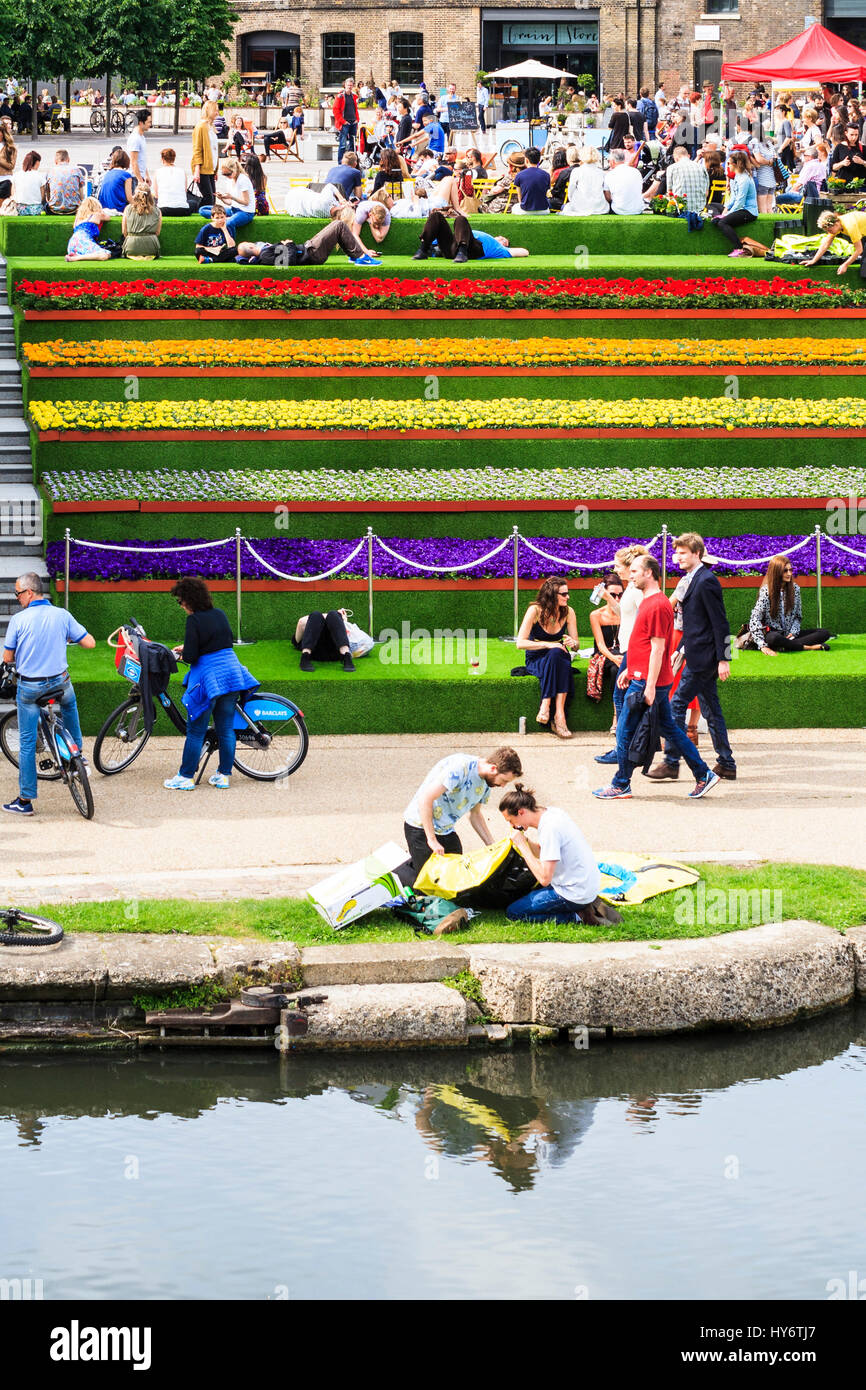 Le soleil sur les marches de la place du grenier par Regent's Canal à King's Cross, Londres, Royaume-Uni, ornée de fleurs et de gazon artificiel, 2014 Banque D'Images
