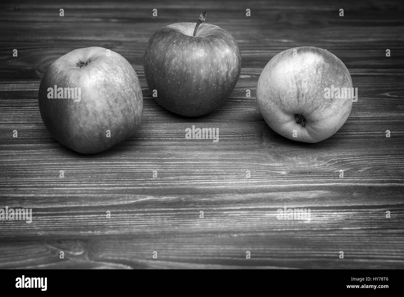 Trois pommes sur fond de bois sombre. Le noir et blanc Banque D'Images