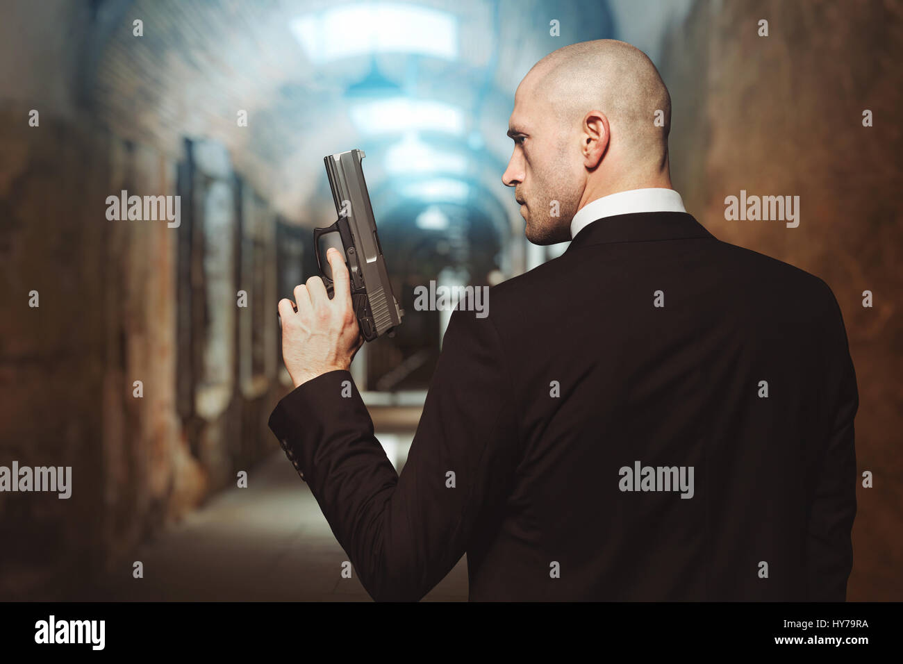 Contract Killer avec gun wallpaper concept, vue arrière. Assassin chauve en cause détient pistolet en main. Secret agent en mission Banque D'Images