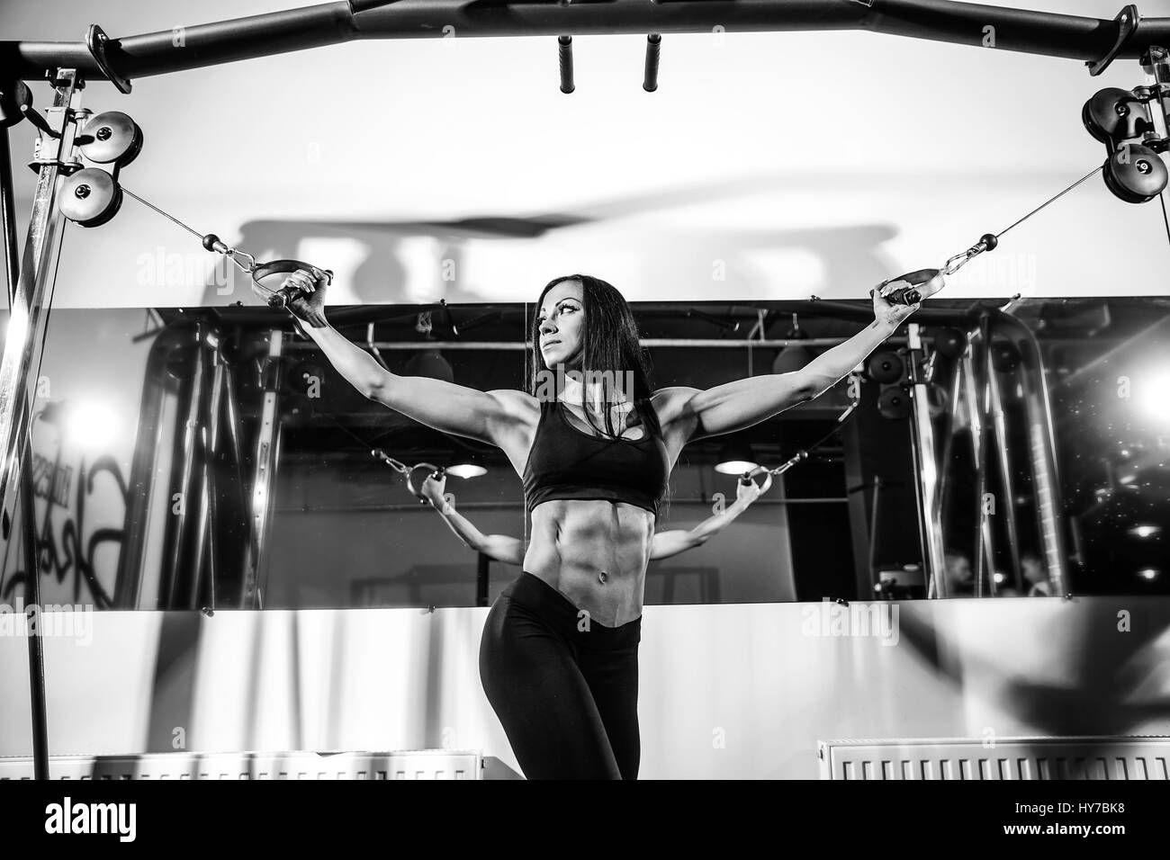 Woman flexing muscles sur le câble de la machine en salle de sport. L'exercice sur les biceps Banque D'Images