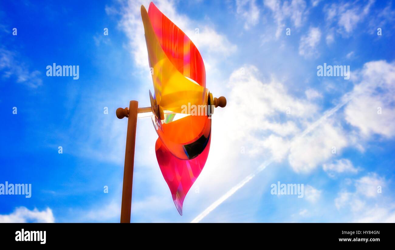 Jouet coloré moulin contre le soleil et un ciel bleu. Banque D'Images Jouet coloré moulin contre le soleil et un ciel bleu. Banque D'Images
