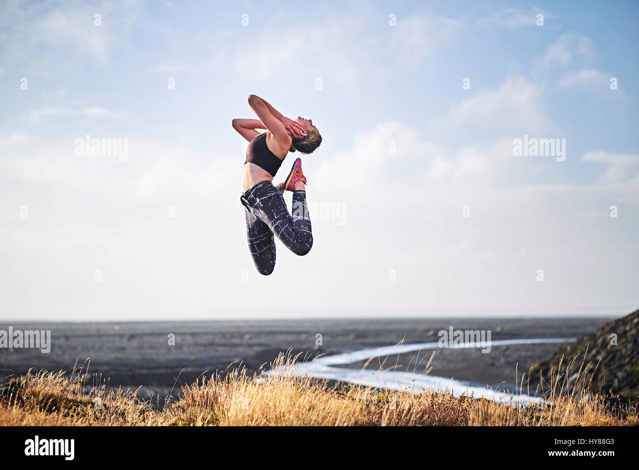 Les jeunes femmes sautant par une route de terre dans le sud de l'Islande Banque D'Images