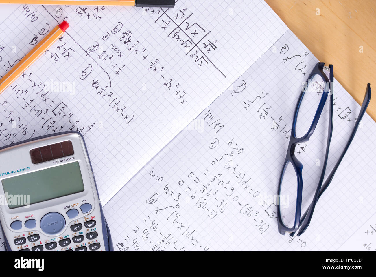 Un bureau avec un livre d'exercice, verres, stylos et une calculatrice pour étudier les mathématiques Banque D'Images