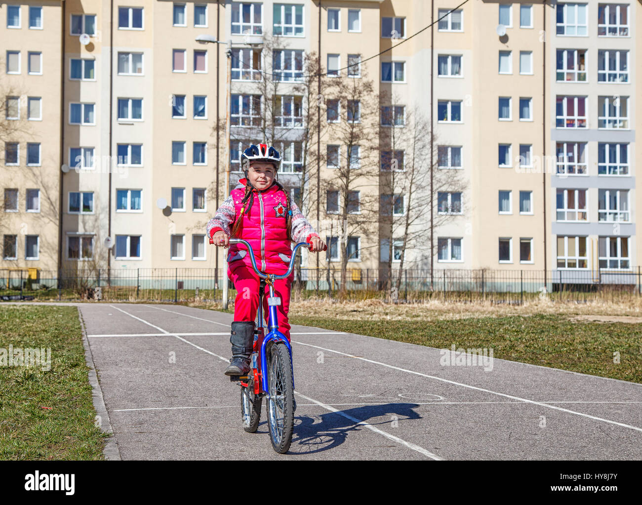 Petite fille dans un costume rouge et un casque de sécurité à bicyclette Banque D'Images