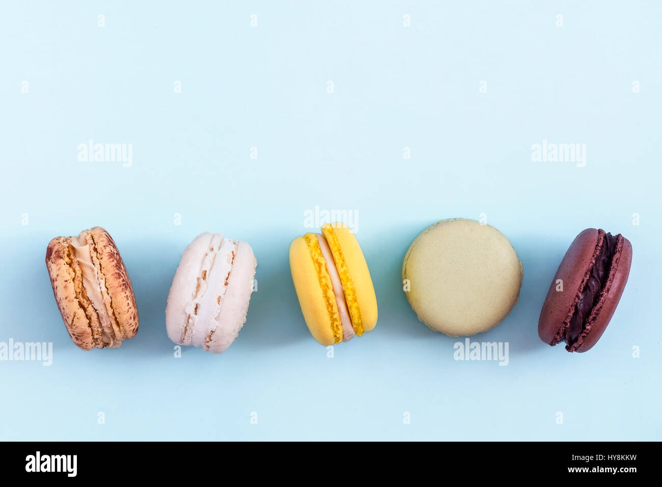 Rangée de macarons français colorés sur fond bleu. Vue de dessus, copiez l'espace pour le texte. Les médias sociaux, blogs concept Banque D'Images