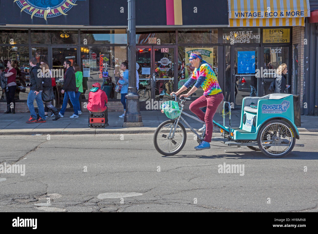 Ann Arbor, Michigan - Un pedicab driver cherche des passagers dans une rue commerçante animée près de l'Université du Michigan. Banque D'Images