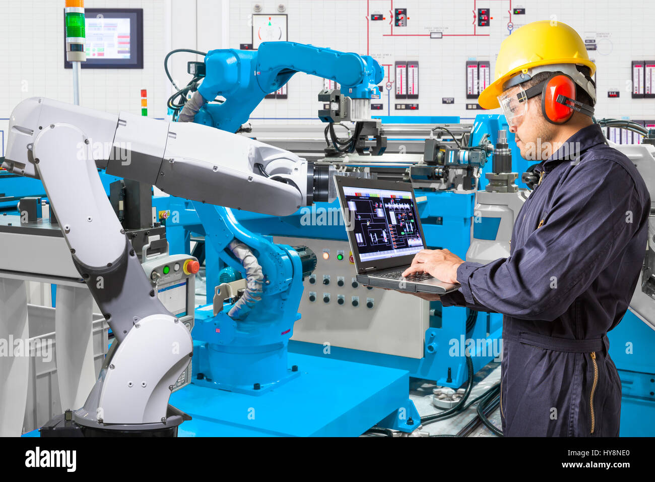 Ordinateur portable à l'aide de l'ingénieur pour l'entretien de la machine-outil main robotisée automatique à l'usine de fabrication industrielle Banque D'Images