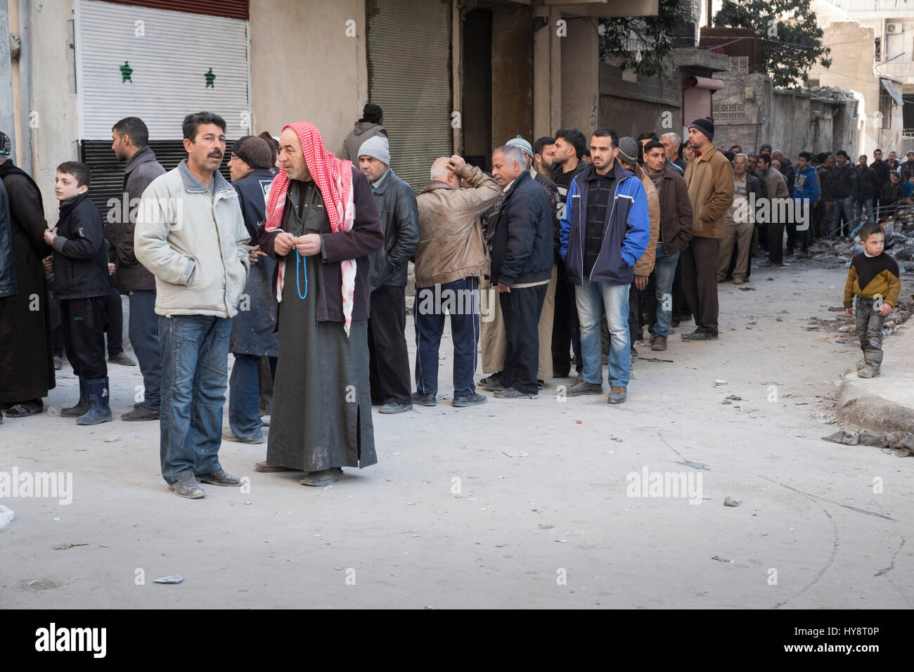 La queue pour la distribution du pain des hommes dans le district Fardous, Alep, Syrie, début 2017 Banque D'Images