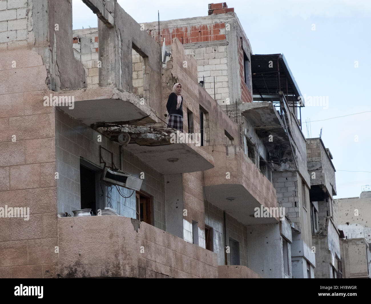 Femme debout dans une maison détruite dans le district Baba Amr à Homs, en Syrie, au début de 2017 Banque D'Images