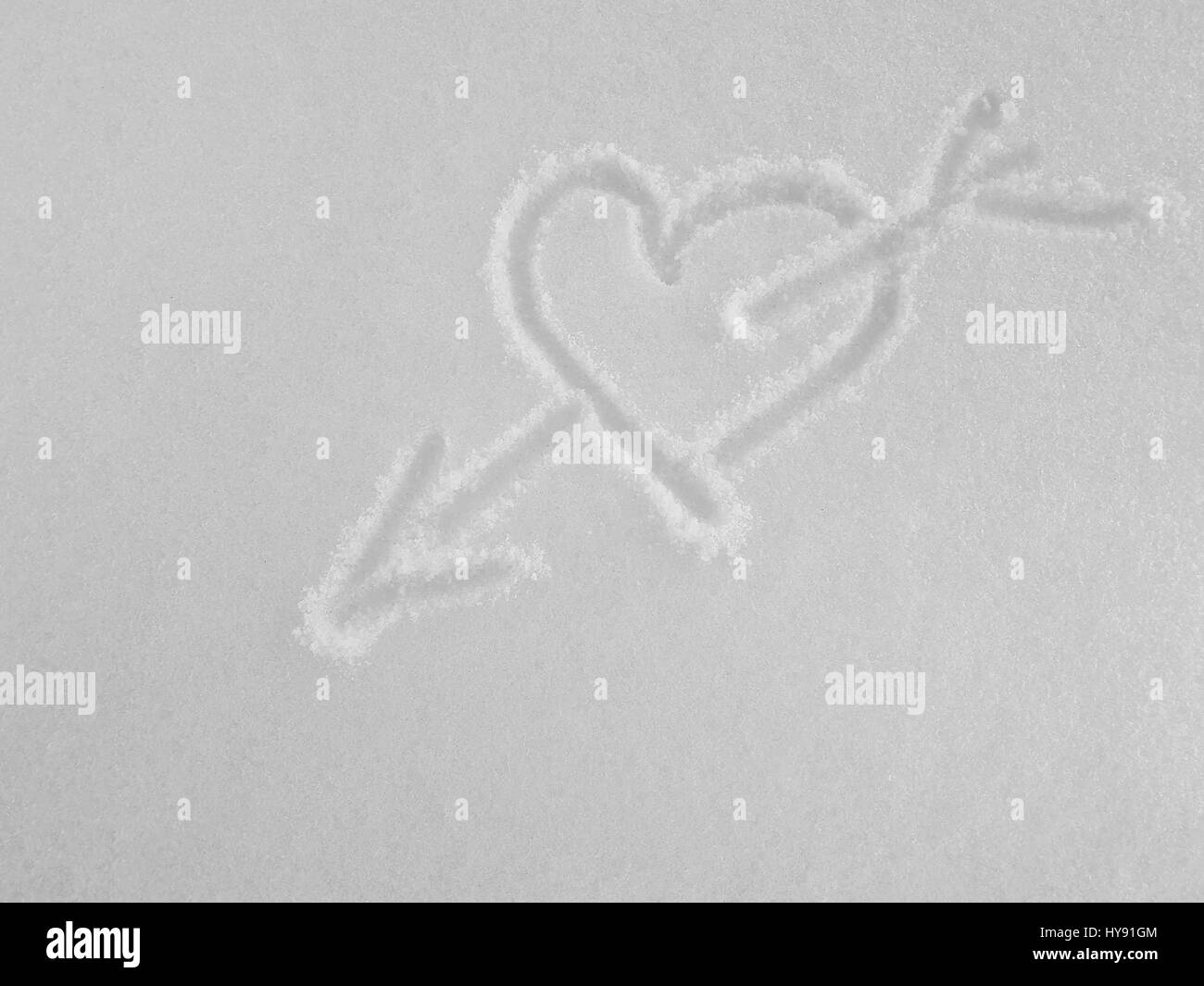 Grand coeur percé par une flèche, en s'appuyant sur un fond blanc de la vraie neige. Banque D'Images