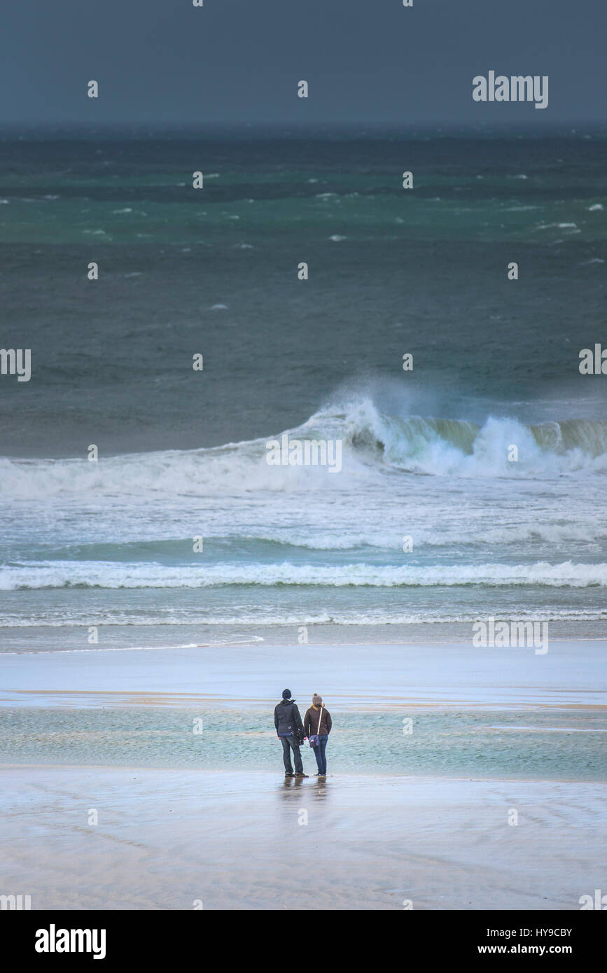 Couple à la plage du rivage de la mer bord de mer Surf Vagues mer grosse tempête de vent météo Royaume-uni Cornwall Fistral de pulvérisation Banque D'Images Couple à la plage du rivage de la mer bord de mer Surf Vagues mer grosse tempête de vent météo Royaume-uni Cornwall Fistral de pulvérisation Banque D'Images