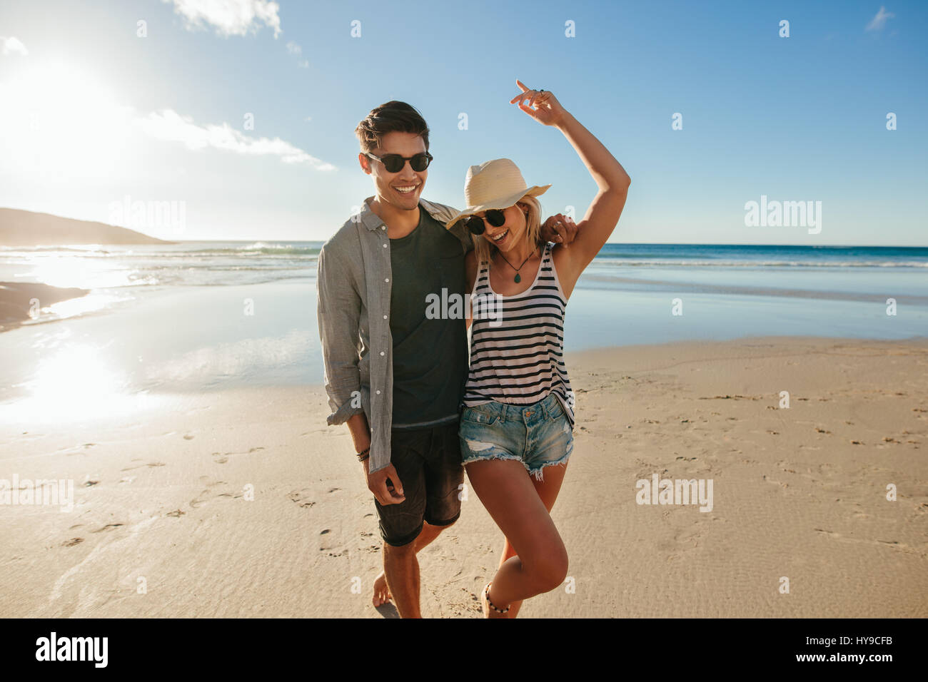Portrait of happy young couple en train de marcher sur le bord de la mer. L'homme et la femme à profiter de l'amour à la plage. Banque D'Images