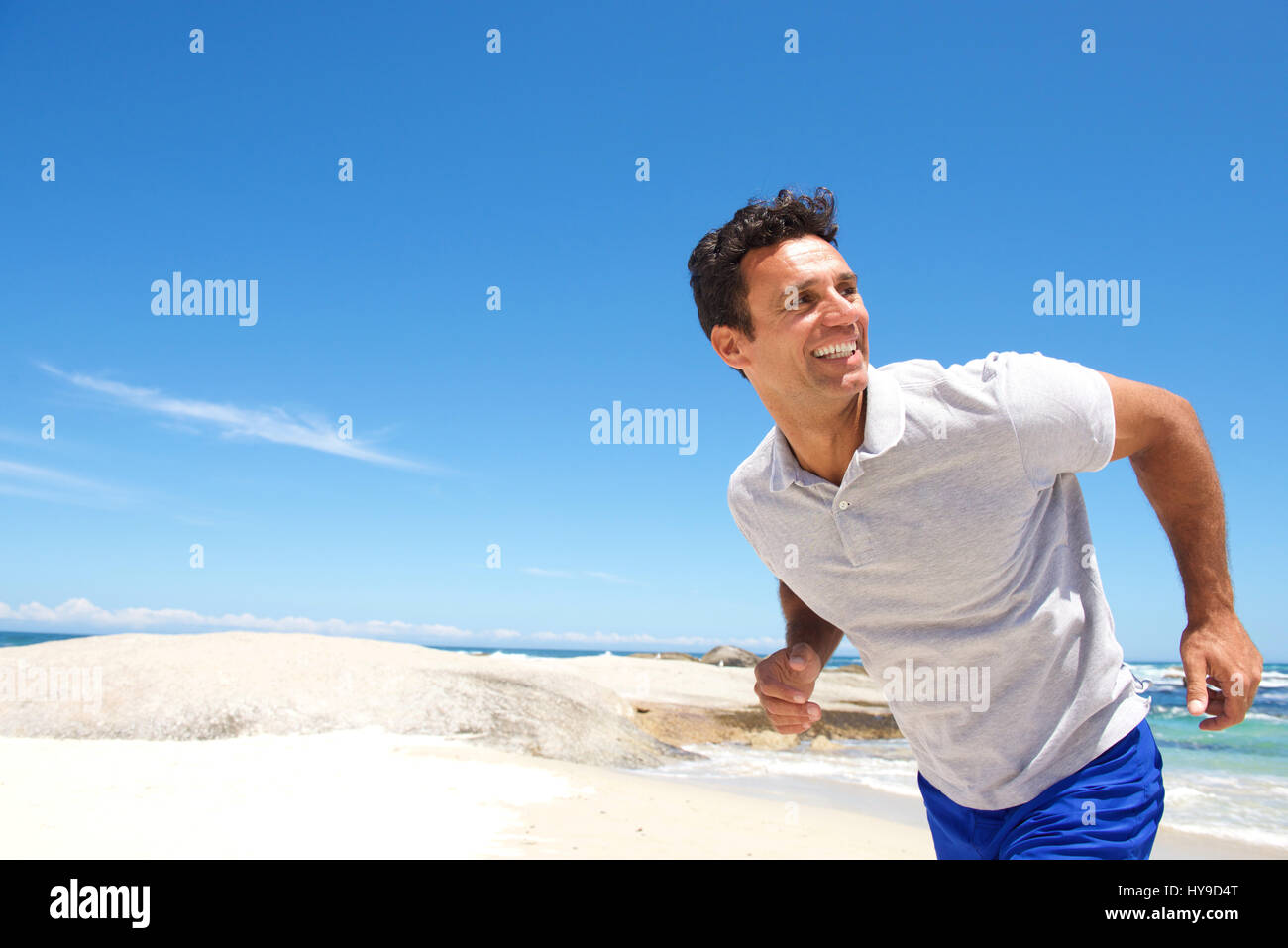 Portrait d'un homme d'âge moyen gai d'exécution sur la plage Banque D'Images