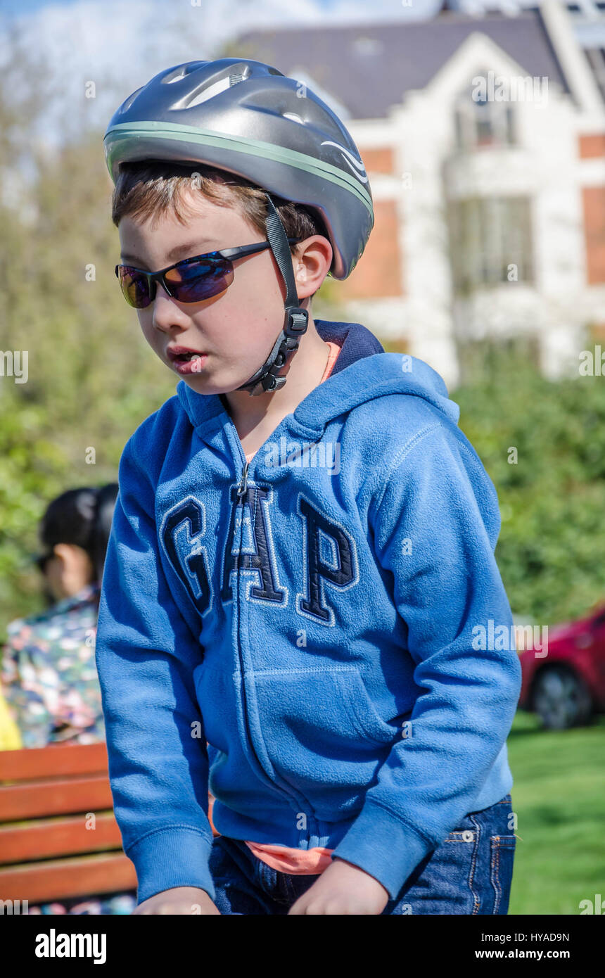 Un garçon dans le parc portant un casque et des lunettes. Banque D'Images
