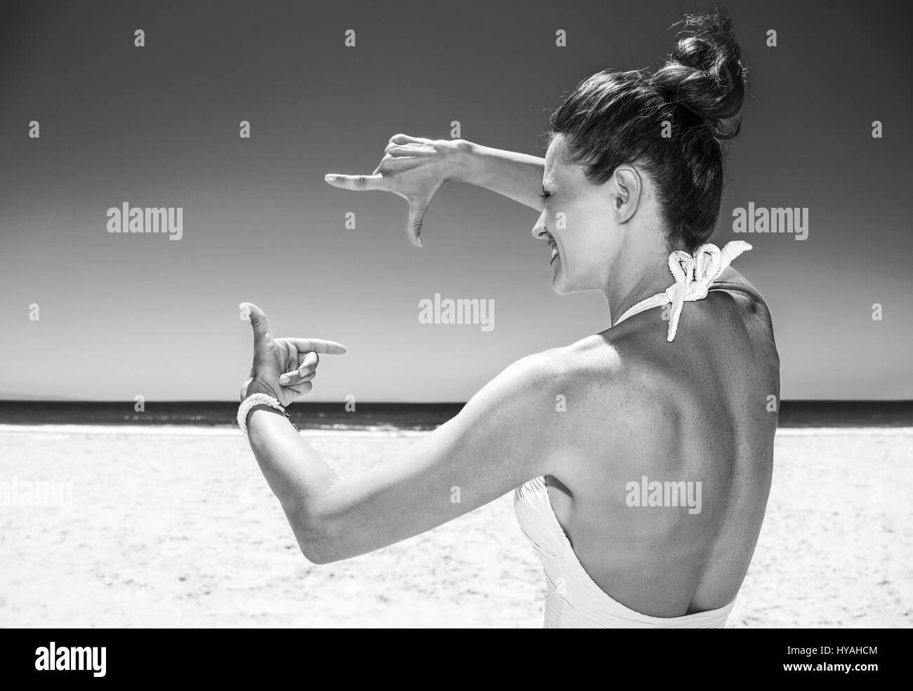 La position de sable blanc mer bleu paradis. Femme heureuse en maillot blanc à sandy beach, un jour ensoleillé, l'ossature à mains Banque D'Images