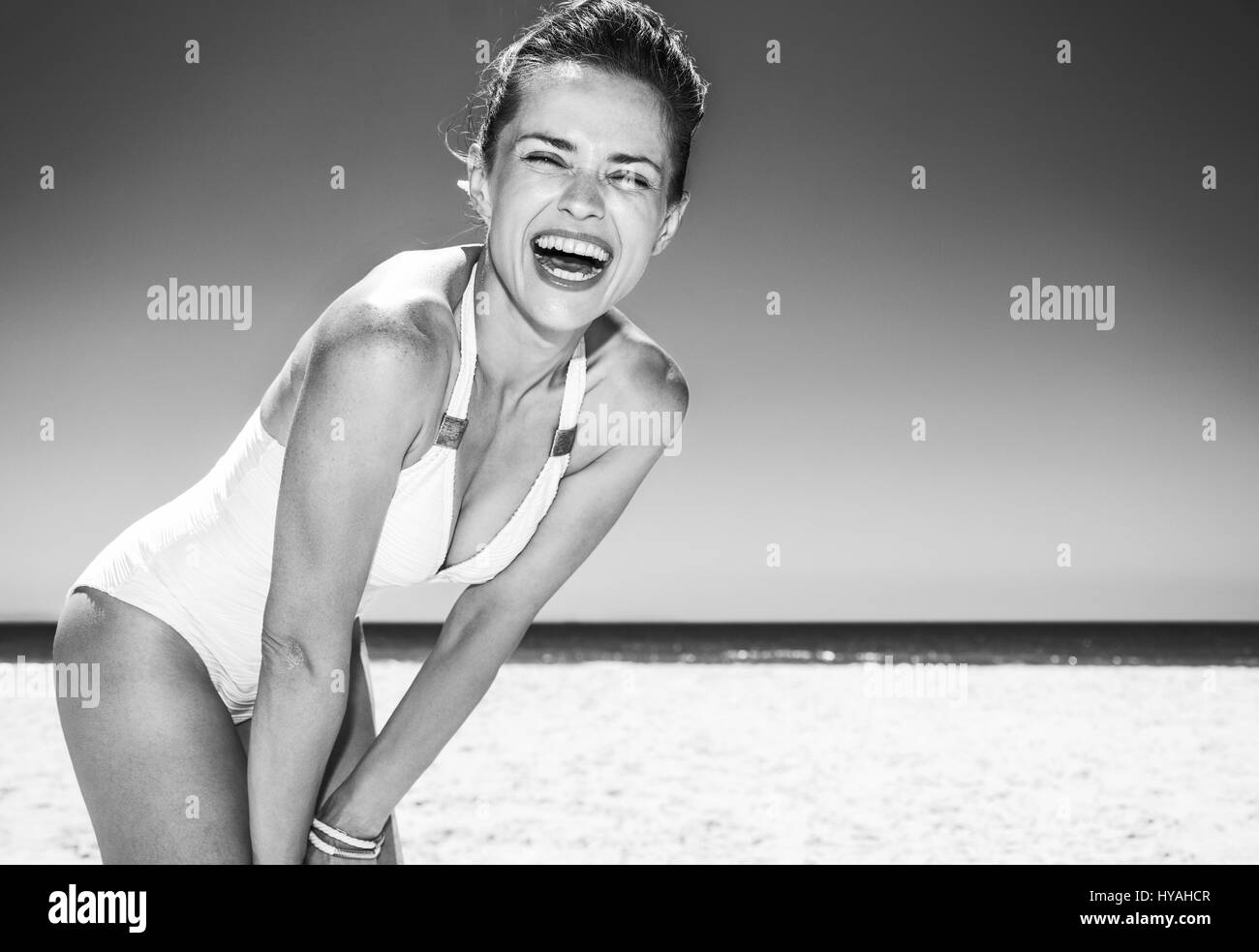 La position de sable blanc mer bleu paradis. Portrait of smiling woman in maillot blanc à plage de sable fin sur une journée ensoleillée Banque D'Images