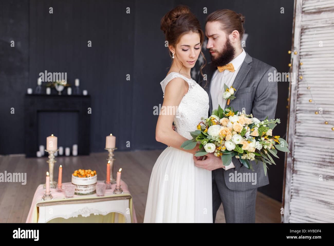 La mariée avec le bouquet dans sa main et le marié se tiennent côte à côte dans un bel intérieur. Se concentrer sur la mariée. Banque D'Images
