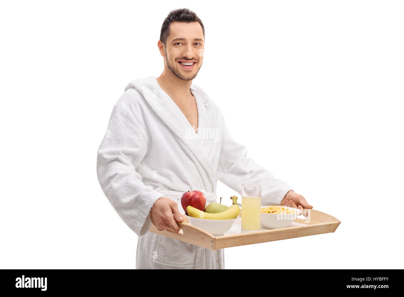 Guy joyeux dans un peignoir tenant un plateau de petit-déjeuner isolé sur fond blanc Banque D'Images Guy joyeux dans un peignoir tenant un plateau de petit-déjeuner isolé sur fond blanc Banque D'Images