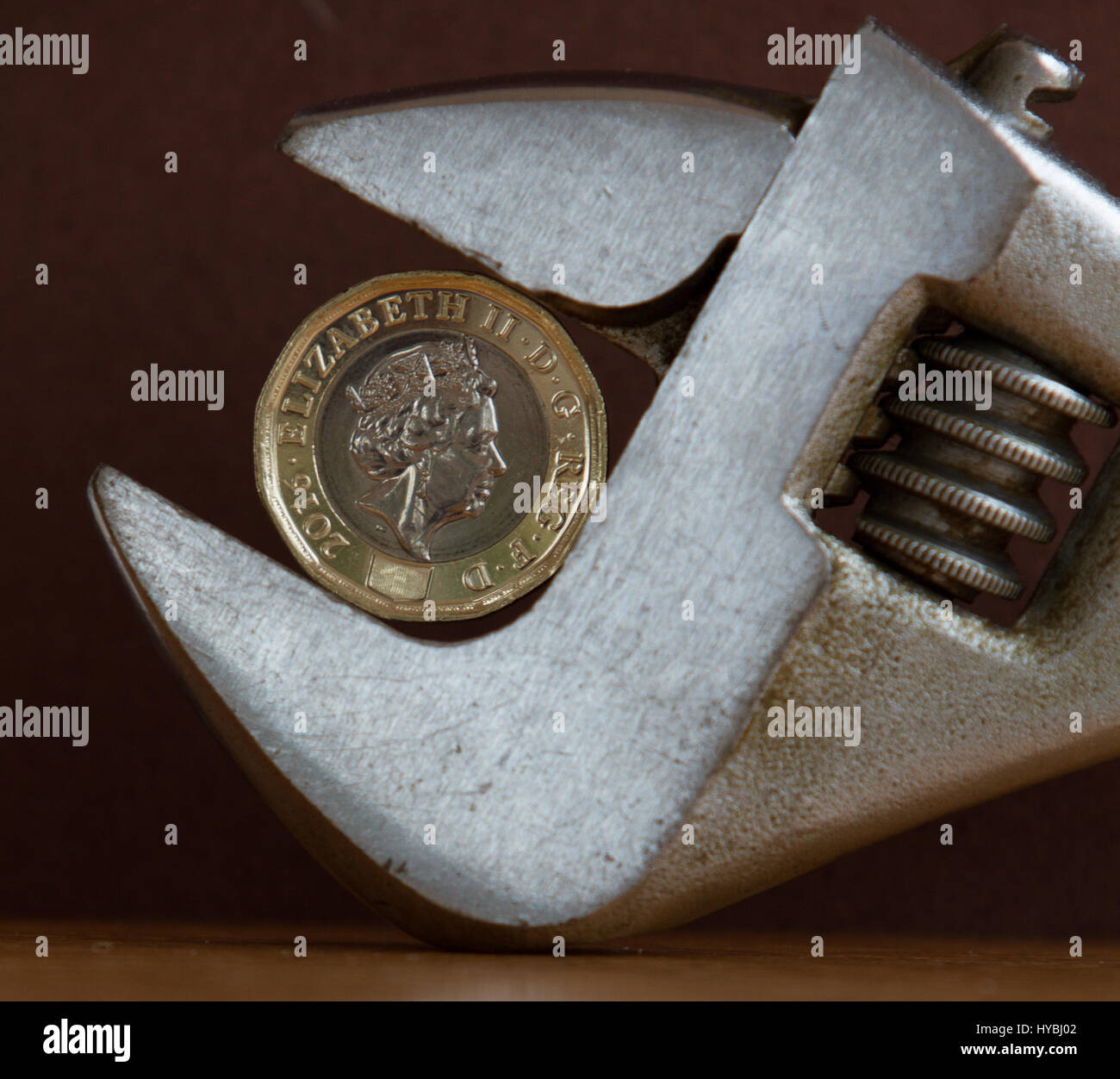 Nouveau livre €1 coin tenue à une clé réglable sur un arrière-plan sombre montrant un squeeze sur les finances Banque D'Images