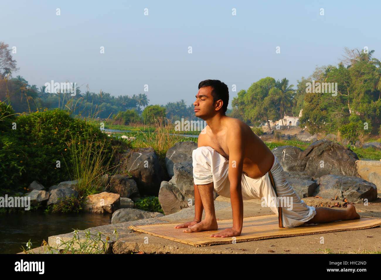Indian man practicing yoga à côté d'une rivière dans le sud de l'Inde. Banque D'Images