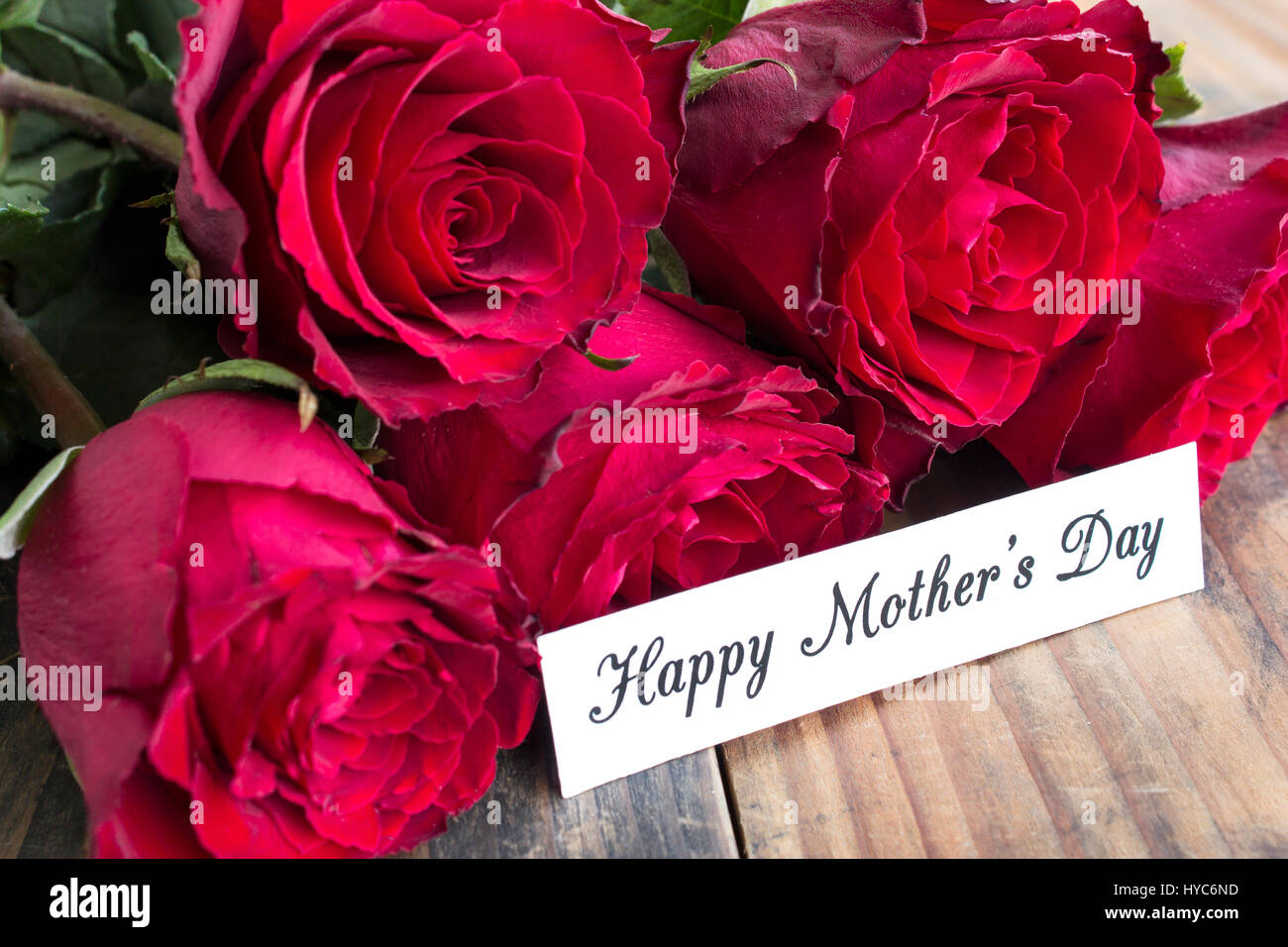 Bonne Fête des mères, carte de souhaits, avec bouquet de roses rouges sur la table en bois rustique. Banque D'Images