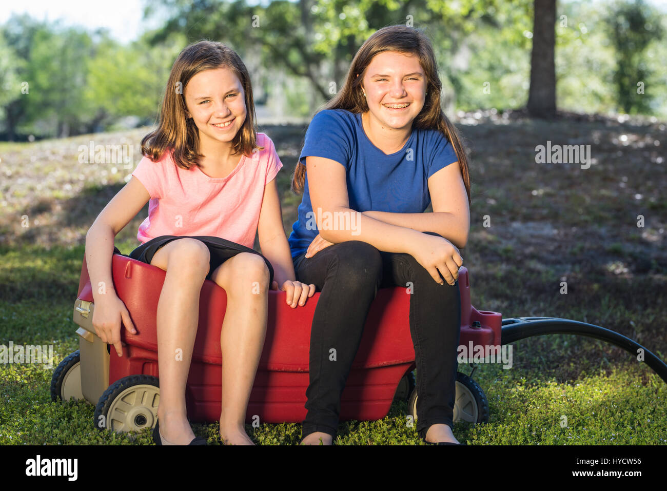 Deux soeurs assis dans Red Wagon Banque D'Images