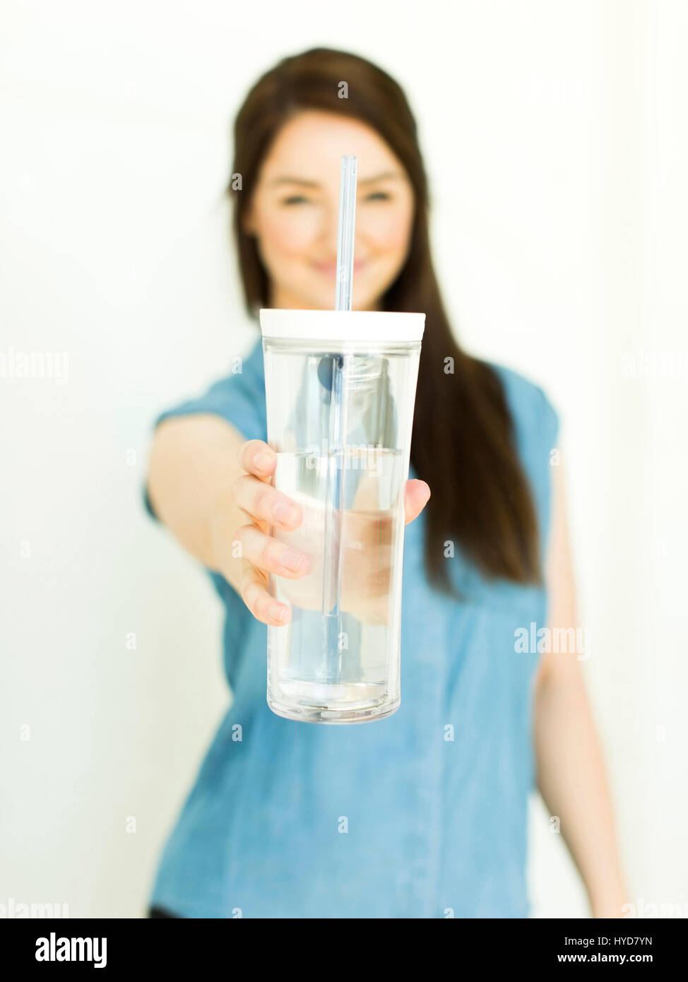 Femme portant le dessus bleu tenant le verre de boisson Banque D'Images