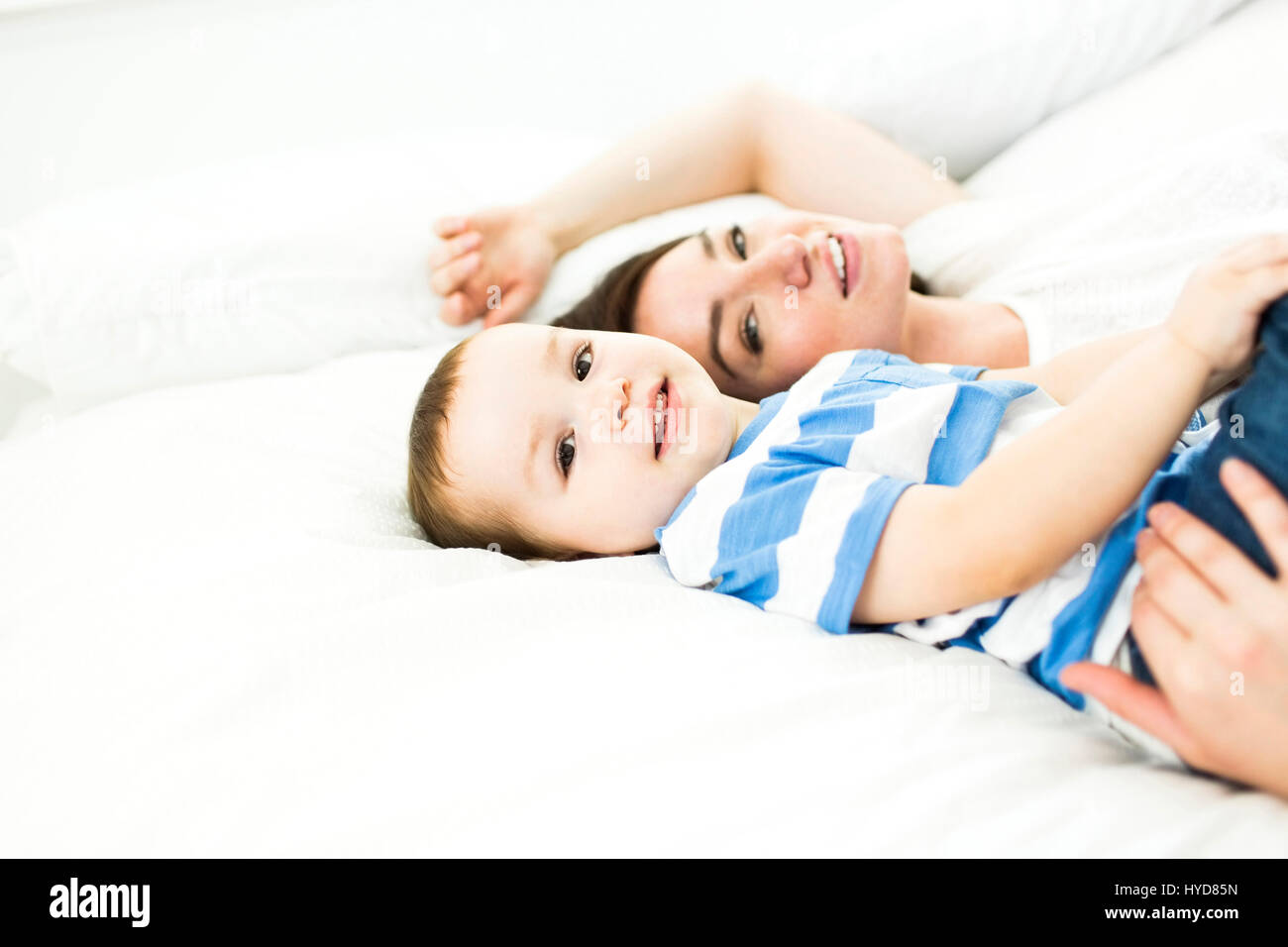 Mère couchée avec son fils (4-5) au lit et souriante Banque D'Images