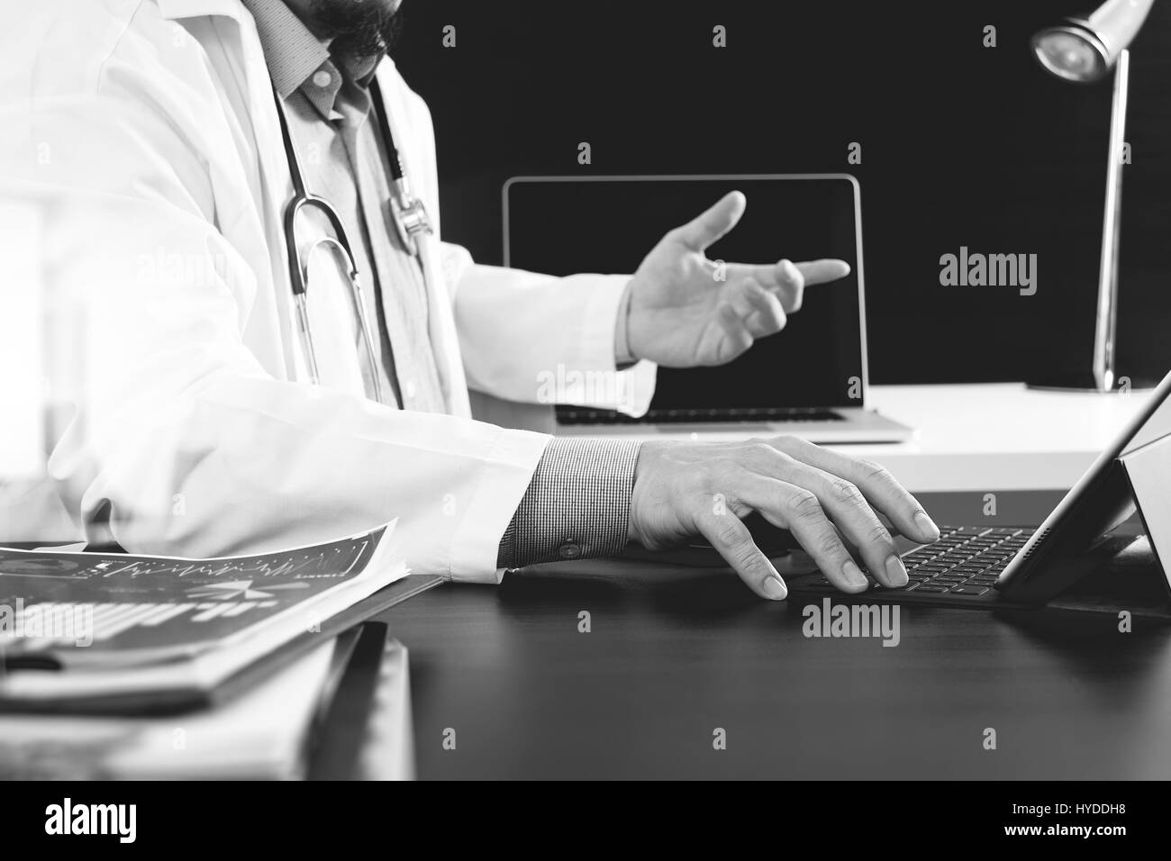 Concept de technologie médicale. Un médecin travaillant avec smart phone et stéthoscope et digital tablet computer in modern office à l'hôpital, noir et blanc Banque D'Images