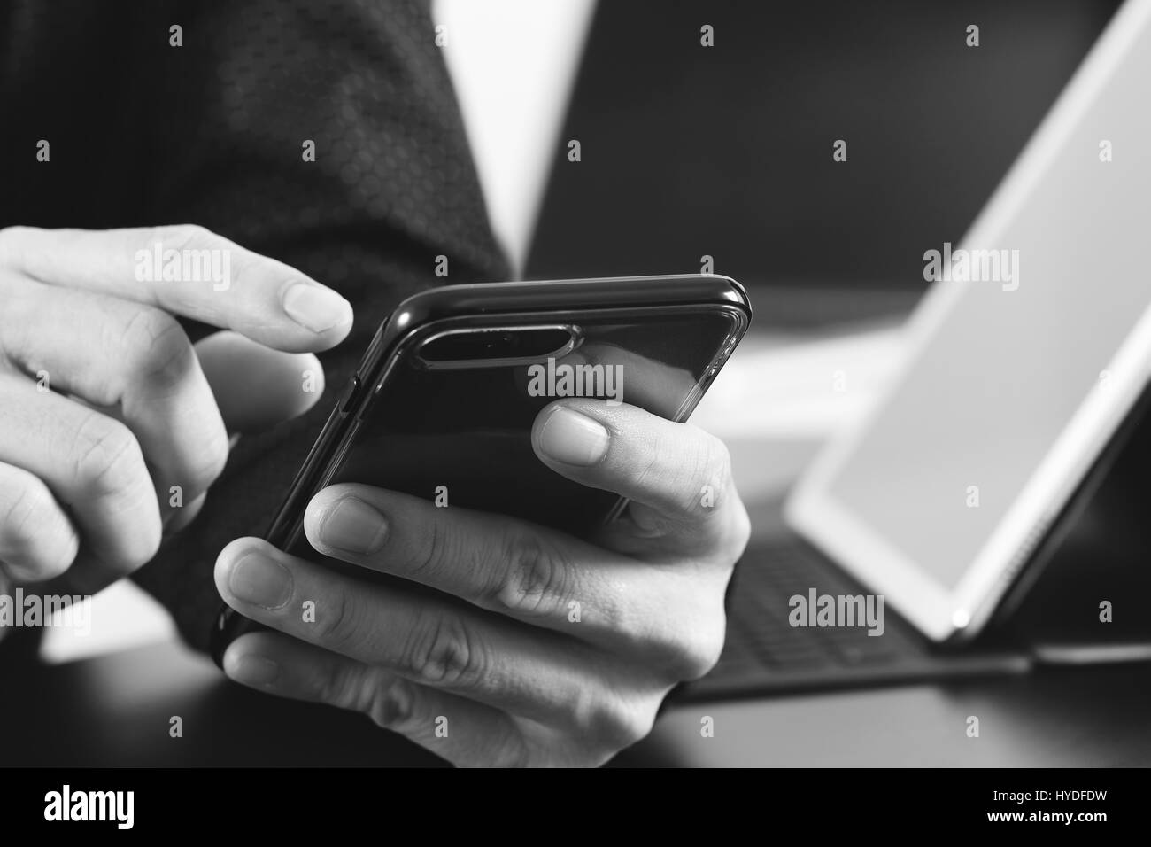 Close up of businessman part travailler avec smart phone et l'ordinateur portable et tablette numérique dans l'ordinateur de bureau moderne, noir et blanc Banque D'Images